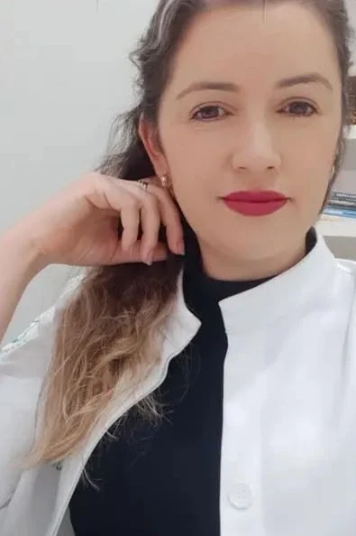 Gisleide de jaleco no consultório, com a mão no rosto